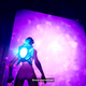 A Fortnite player stands before a looming purple cube.